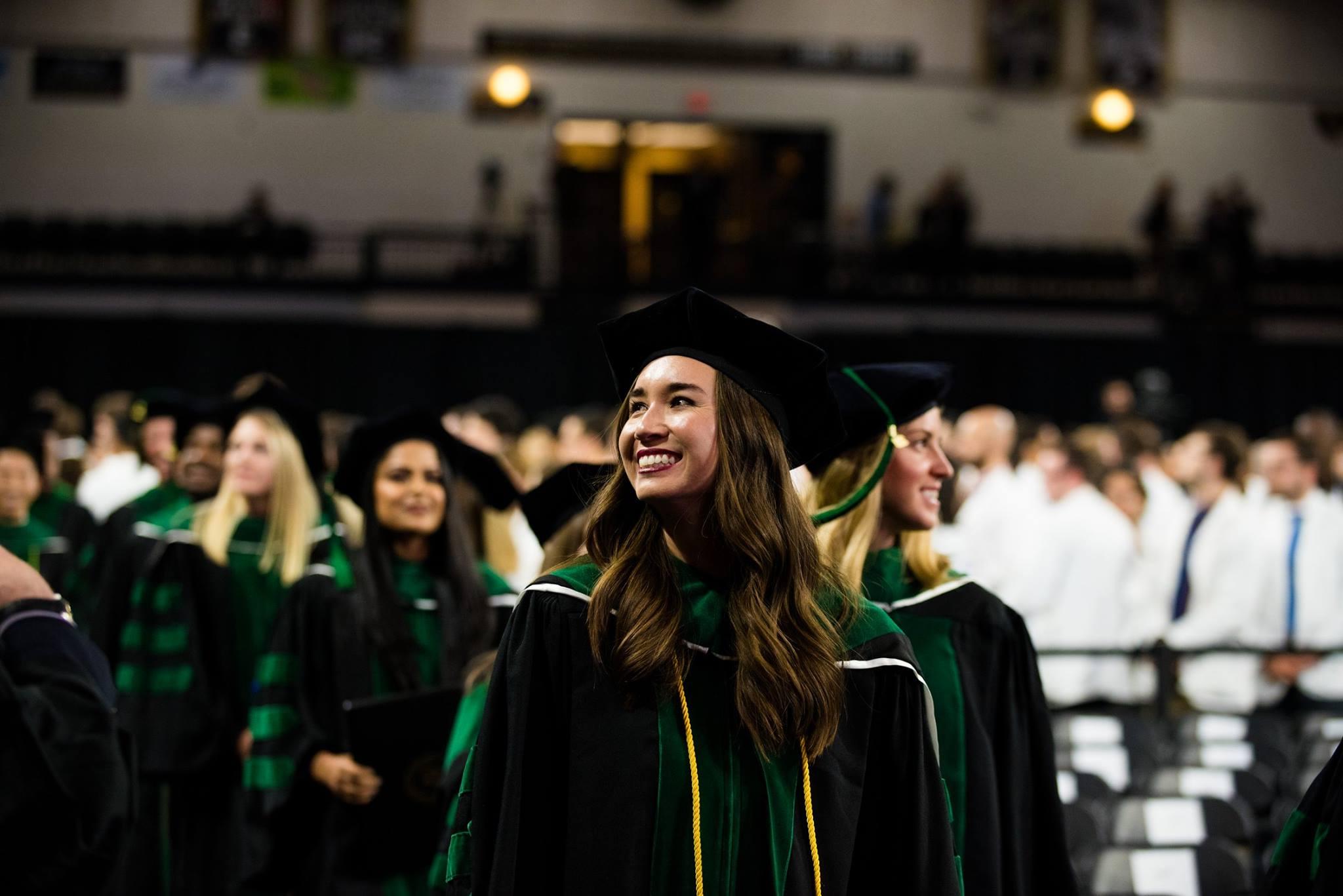 Smiling student wearing cap and gown at graduation ceremony.