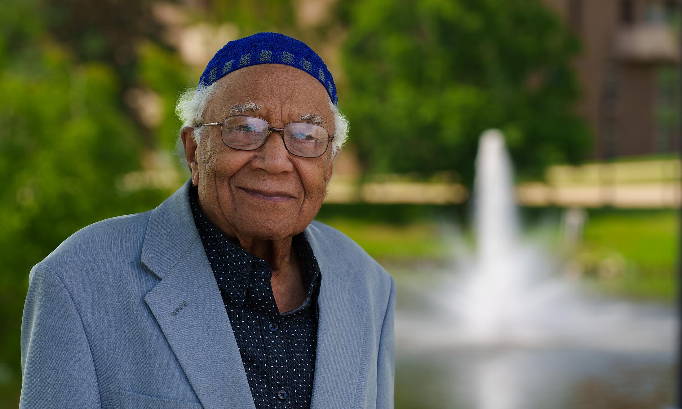 A man smiling with a fountain in the background