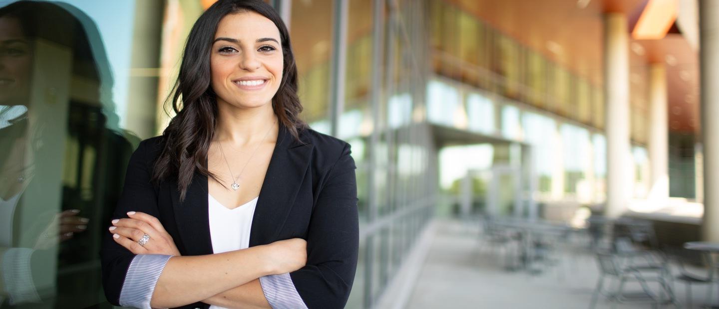 Woman standing and smiling at camera with arms crossed